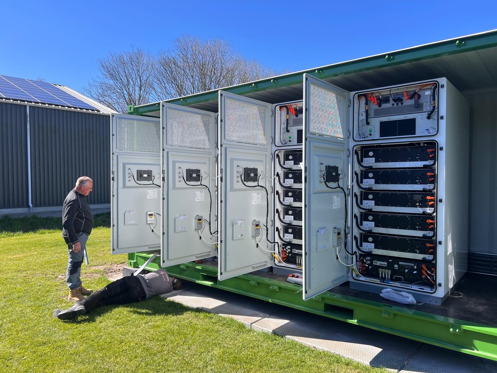 Gecontaineriseerd batterijsysteem met geopende kastdeuren en monteurs